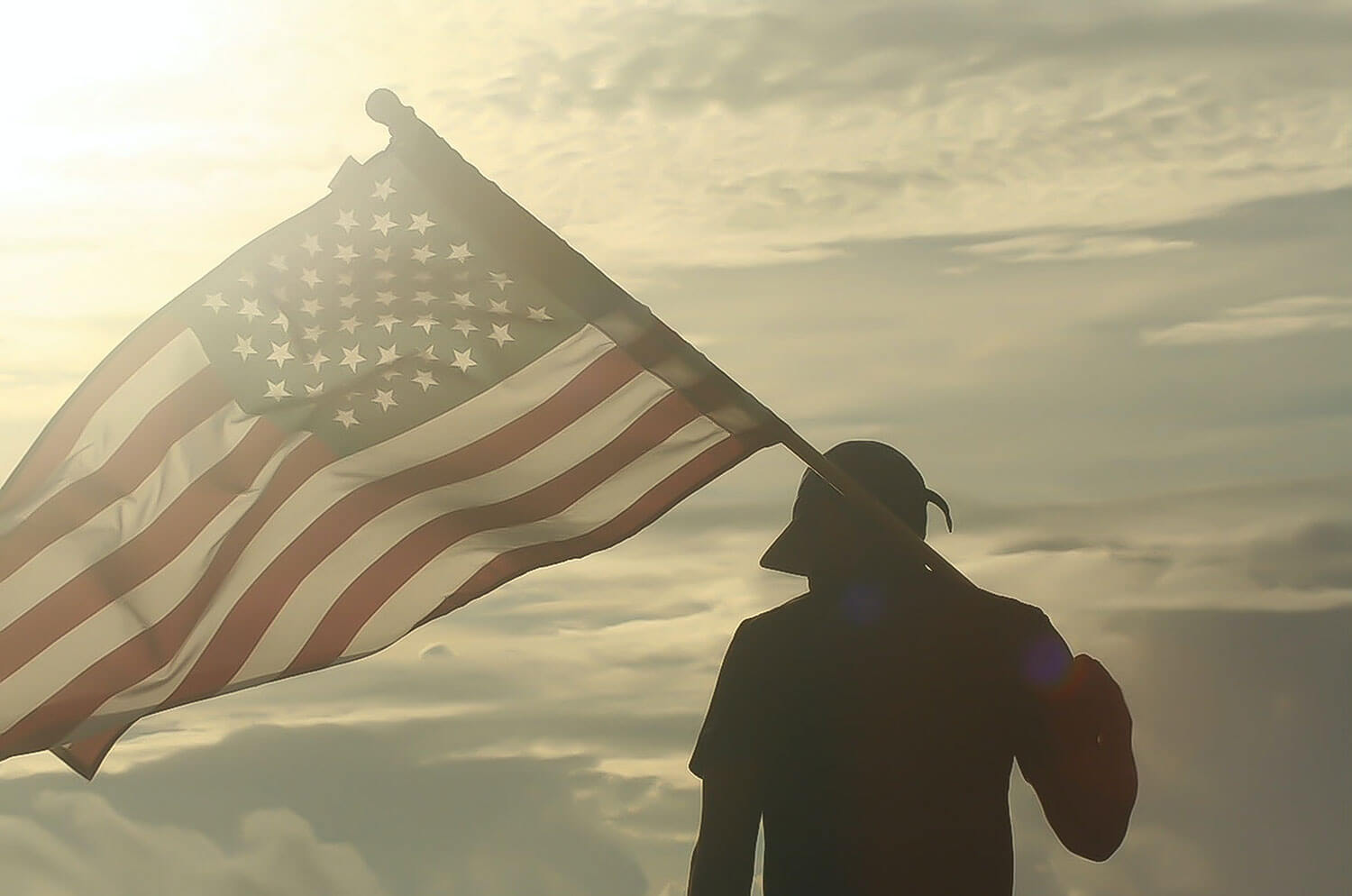 A silhouette of a man carrying the American Flag on his shoulder