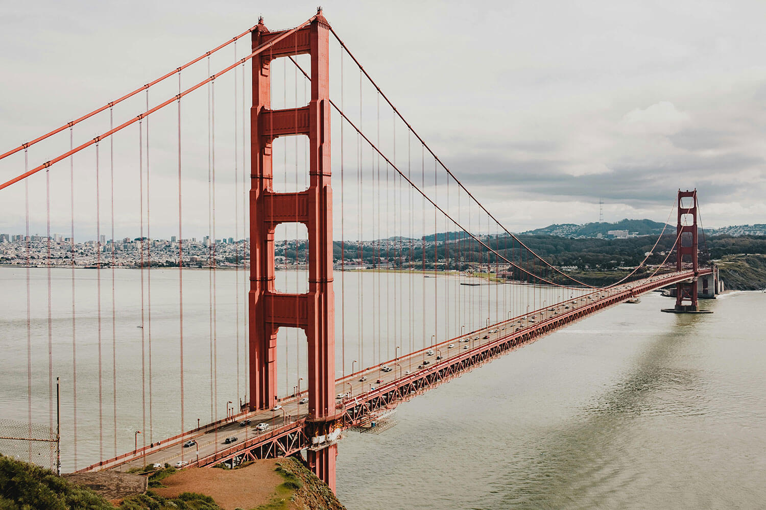 Golden Gate bridge on a cloudy day with cars crossing.