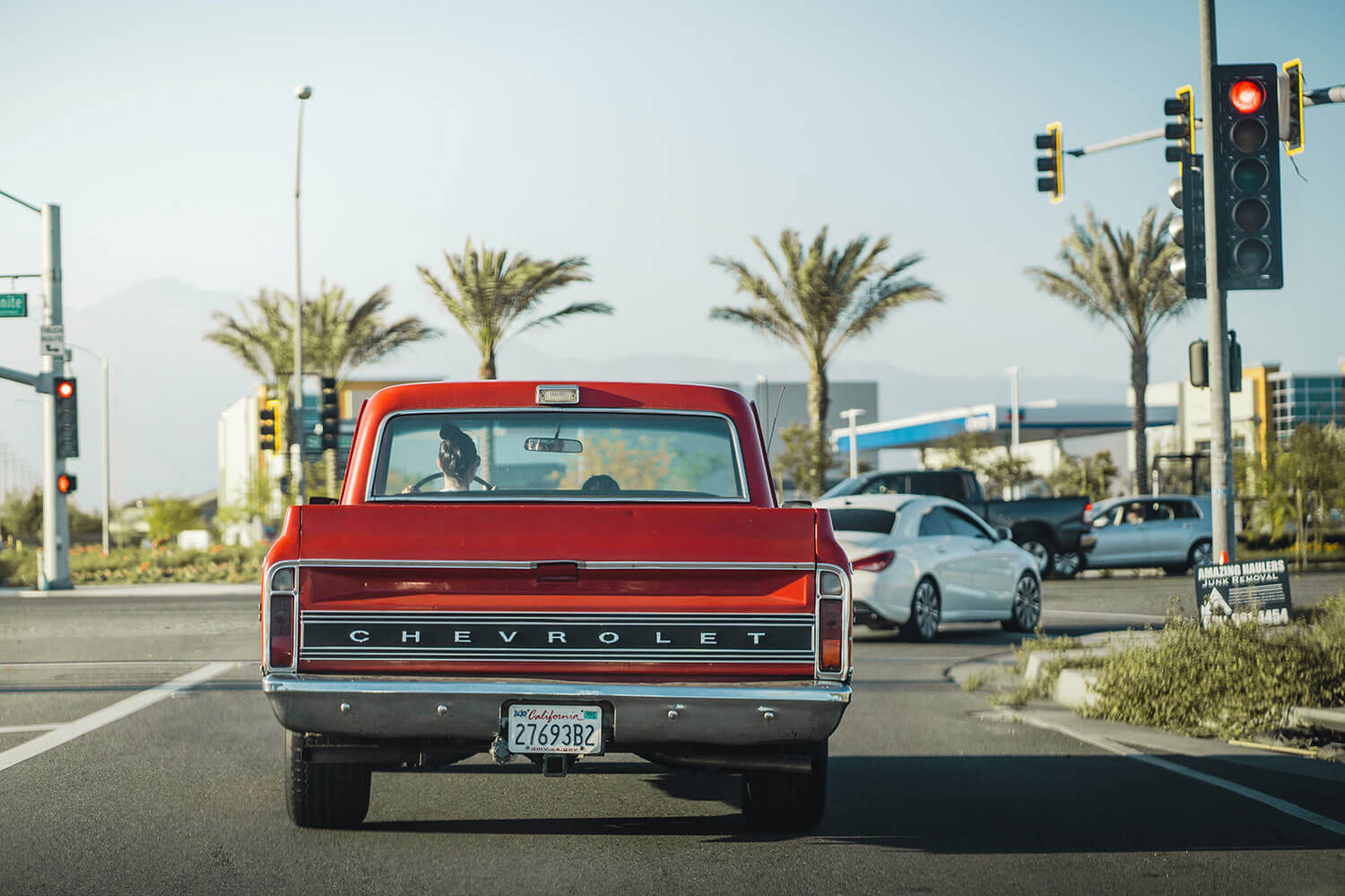 A red vintage Chevrolet Pickup truck stopped at a redlight