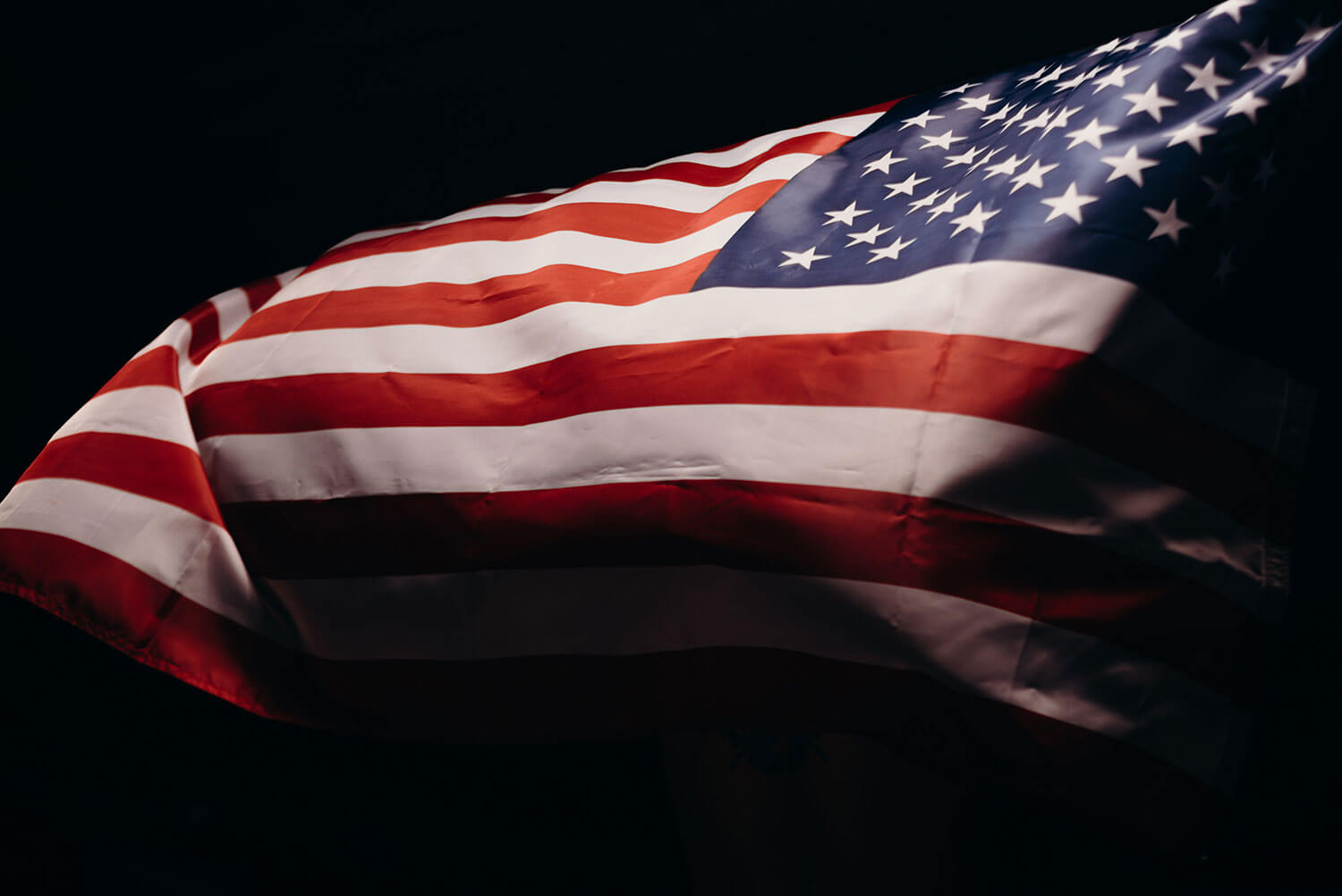 An American flag illuminated and in motion with a black background