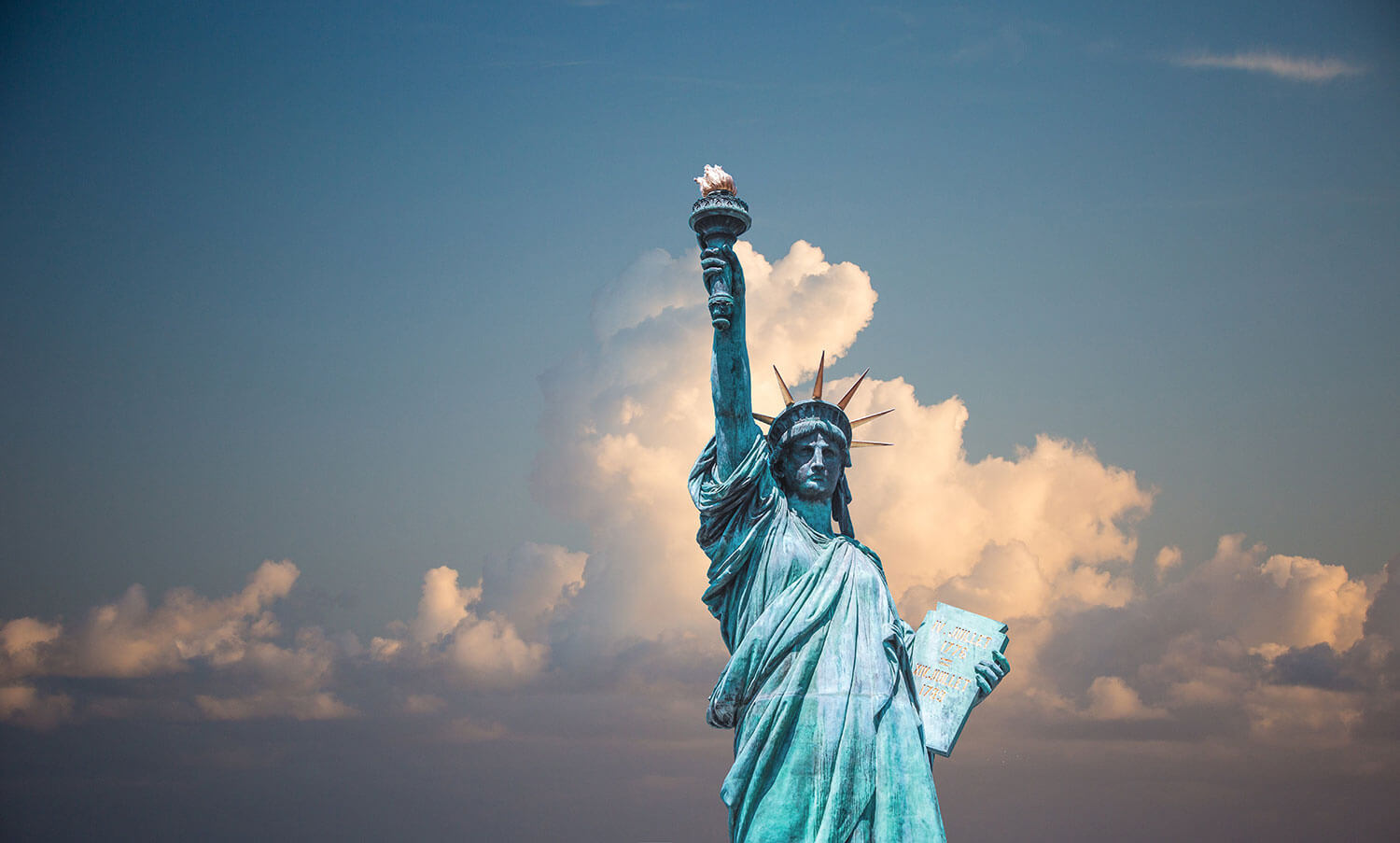 The Statue of Liberty with large cumulus clouds behind off in the far distance