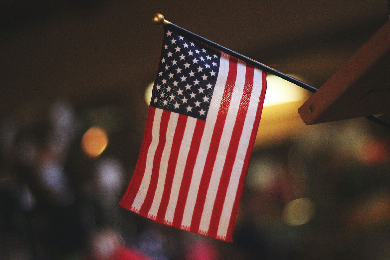 A miniature American flag in focus with soft lighting out of focus in the background